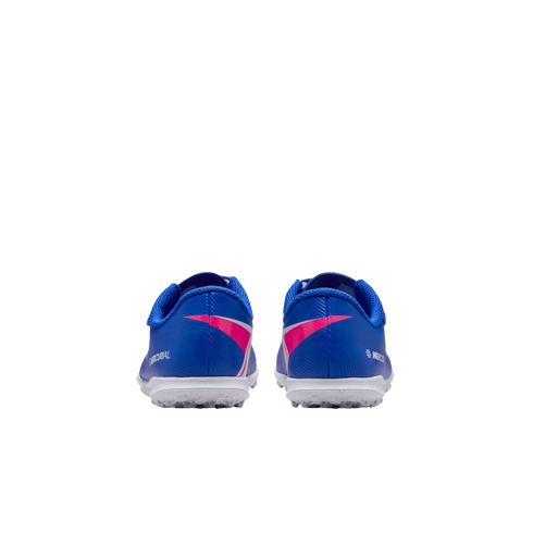 Rear view of blue Nike Mercurial turf shoes with pink accents and white outsoles, set against a solid black background.