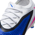 Close-up of a white Nike soccer cleat featuring a blue and black panel with "NIKE VENOMSKIN" branding, white laces, and pink accents.