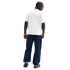 Rear view of a person with braids wearing a white T-shirt, navy baggy pants, and blue sneakers against a solid black background.