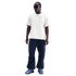 A man wearing a cream Nike CFC t-shirt, navy cargo pants, and blue sneakers against a black background.