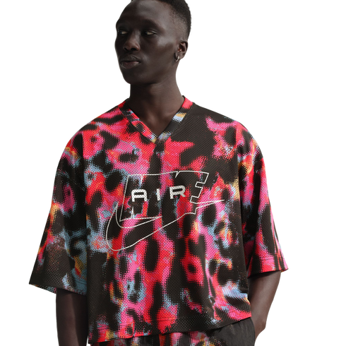 Man wearing a vibrant Nike Air jersey with a colorful abstract halftone pattern and white logo outline. Plain white background.