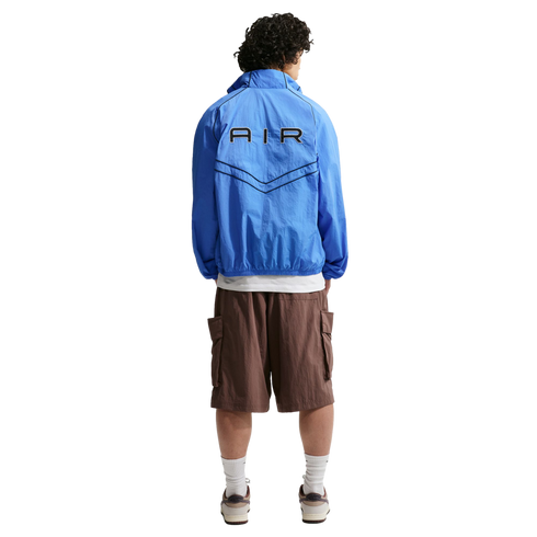 Back view of a person wearing a blue "AIR" windbreaker jacket, brown cargo shorts, and sneakers.