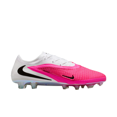 Side profile of a white and vibrant pink Nike soccer cleat with black Swoosh logos and an iridescent studded sole, isolated on a white background.