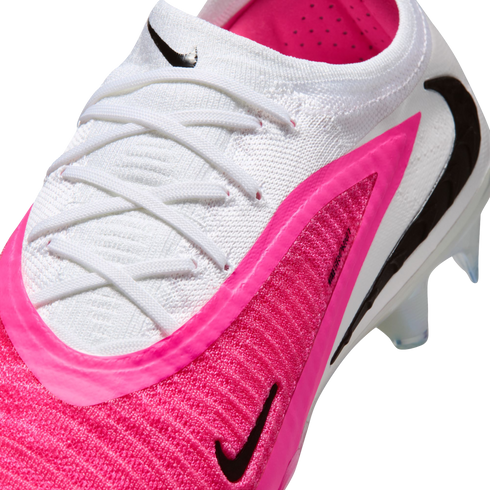 A close-up of a white and bright pink Nike soccer cleat with black swooshes, white laces, and textured Gripknit material.