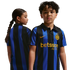 Two children model the black and blue striped Inter Milan home jersey with gold logos, showing both front and back views against a white background.