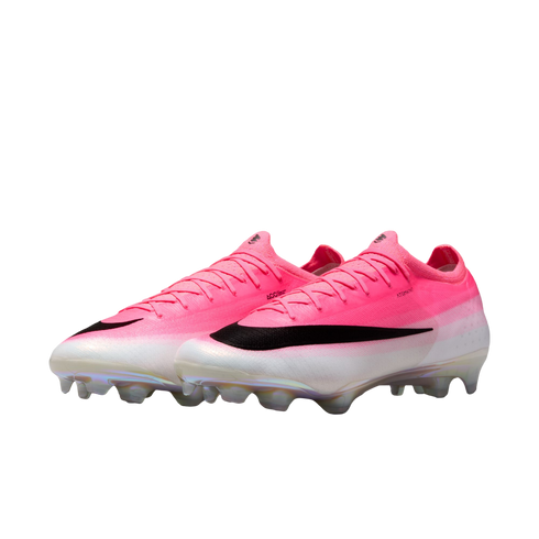A pair of pink and white Nike soccer cleats with a large black swoosh and iridescent studs on a plain white background.