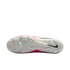 The white sole of a Nike soccer cleat with light blue studs, a black swoosh on the heel, and a pink and white upper.