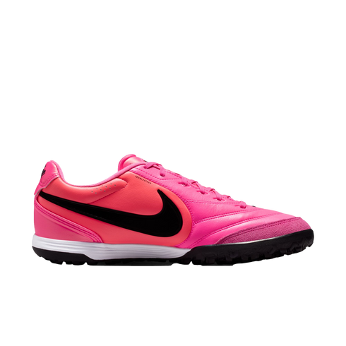 A side view of a bright pink Nike soccer turf shoe with a black Swoosh and white midsole, isolated against a white background.