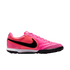 A side view of a bright pink Nike soccer turf shoe with a black Swoosh and white midsole, isolated against a white background.