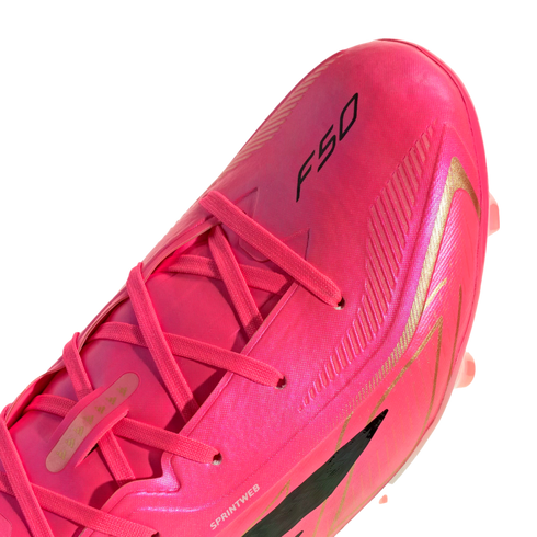 Close-up of a bright pink soccer cleat with gold accents and the black "F50" logo on its upper. The cleat features pink laces and is shown against a white background.