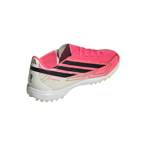 Adidas soccer turf shoe featuring a bright pink and white upper, black iconic stripes, and gold accents, including a World Cup trophy icon on the heel.
