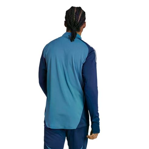 Rear view of a person with braided hair wearing a two-tone blue athletic long-sleeve top and matching pants against a solid black background.