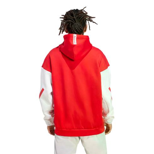 Back view of a person with dreadlocks wearing a red and white Arsenal hoodie and light-colored pants against a white background.
