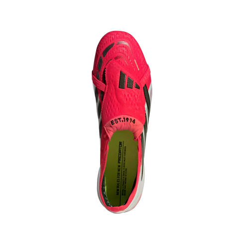 Top-down view of a bright pink Adidas Predator football boot with a fold-over tongue and lime green insole, set against a solid black background.