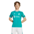 A young person with wavy brown hair wearing a teal Liverpool FC soccer jersey and white shorts, standing against a solid black background.