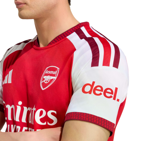 Man wearing a red and white Arsenal FC home jersey with visible club crest and "deel." sleeve sponsor.