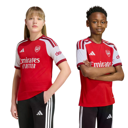 A girl and a boy pose side-by-side in official Arsenal home football kits against a plain white background.