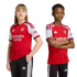 A girl and a boy pose side-by-side in official Arsenal home football kits against a plain white background.