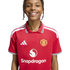 A smiling young person with braided hair wears a red Manchester United football shirt featuring the Snapdragon sponsor logo, set against a white background.