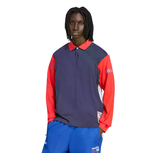 A person with dreadlocks models a navy and red long-sleeve Adidas polo shirt and blue athletic pants, both featuring "World Cup USA 94" branding, set against a solid black background.