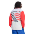 A rear-view shot of a person with long dreadlocks wearing a white long-sleeved shirt with red sleeves and blue pants against a black background. The back of the shirt features the "WorldCupUSA94" logo above a graphic of a soccer ball and red stripes.