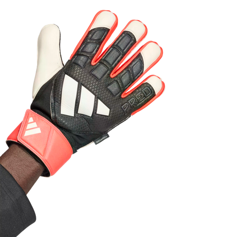 An Adidas Predator goalkeeper glove in black, coral, and white, featuring the brand's logo and "PRED" text. The glove is worn on a hand against a plain white background.