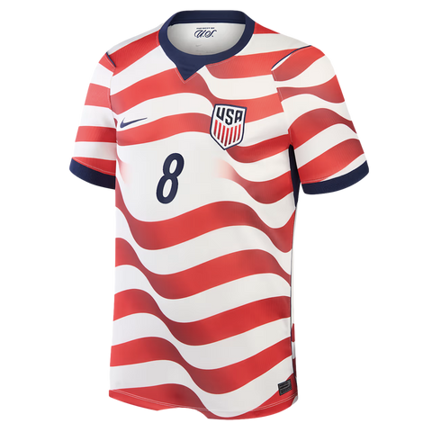 A soccer jersey for the United States national team against a black background. The jersey features wavy horizontal red and white stripes. It has a blue Nike swoosh on the right chest, a US soccer crest on the left chest, and the number 8 in dark blue in