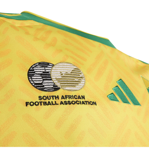 Close-up of a yellow South Africa soccer jersey featuring the embroidered South African Football Association crest and green Adidas logo.