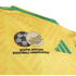 Close-up of a yellow South Africa soccer jersey featuring the embroidered South African Football Association crest and green Adidas logo.