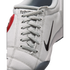 Close-up of a light gray textured Nike sneaker with gray laces and a black swoosh logo on the side.